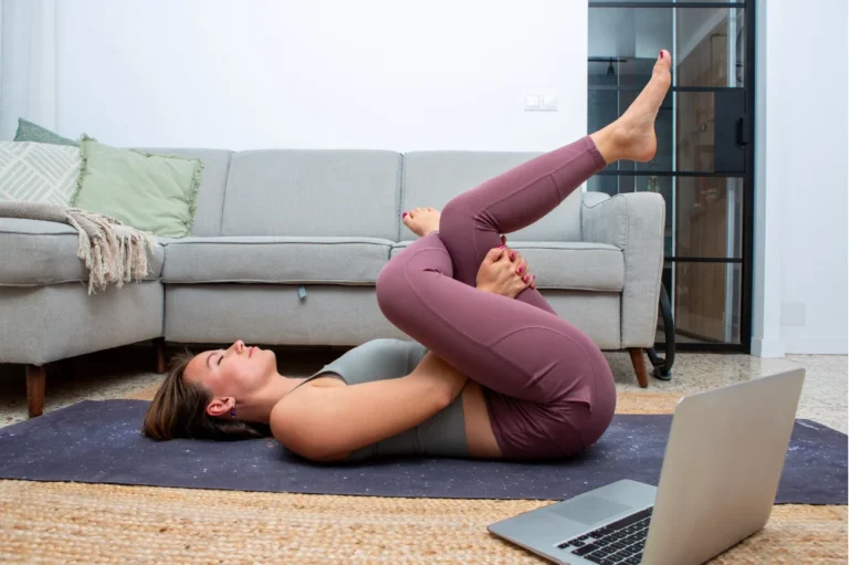 Woman lying on a yoga mat performing a supported figure-4 stretch for hip mobility