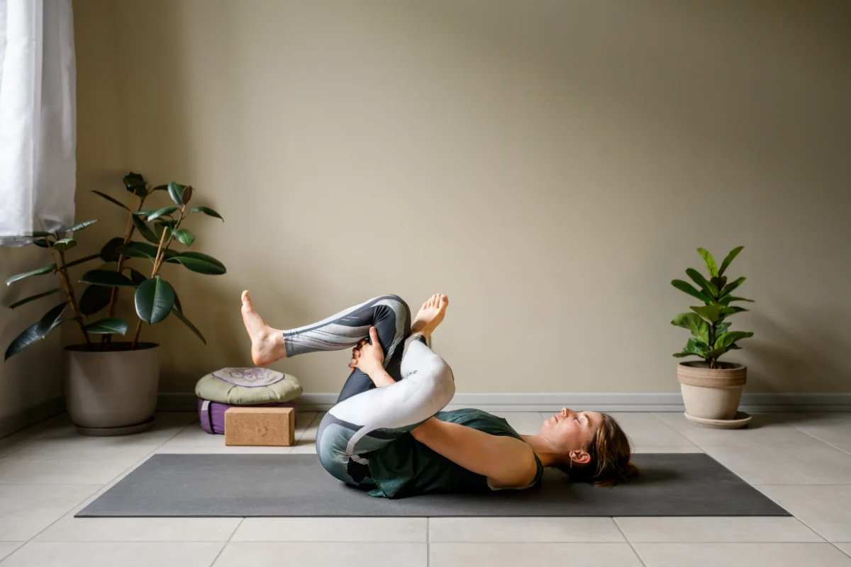 Woman doing a figure-4 stretch lying on her back on a yoga mat