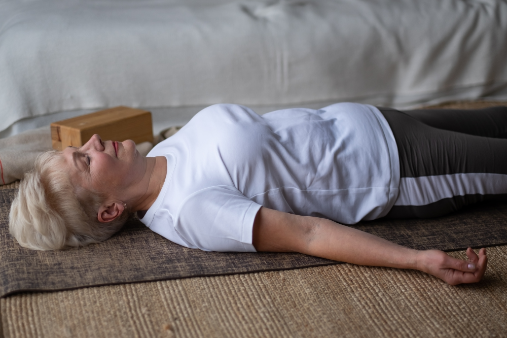 Person lying on their back on a yoga mat, a gentle rest position for flare recovery