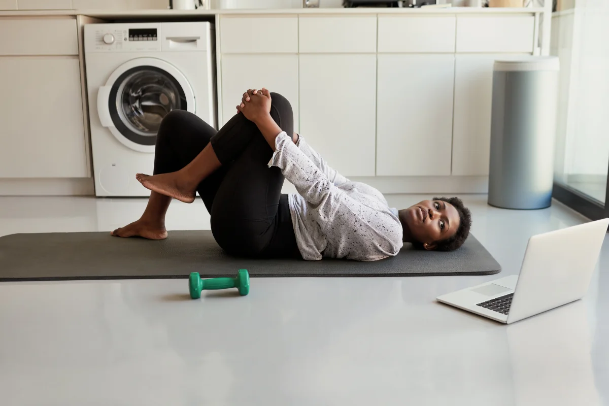 Woman doing a supported knees-to-chest stretch on a mat to ease muscle tension