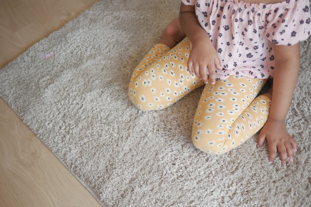 Toddler W-sitting on a rug, a sitting position many hypermobile kids default to